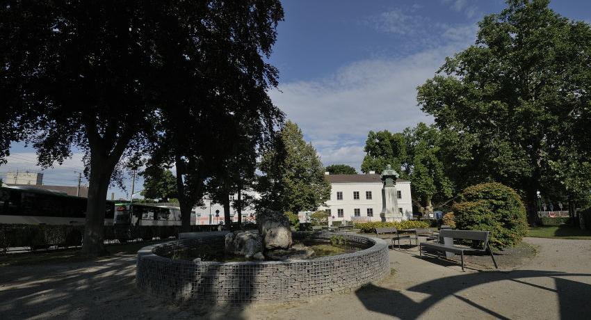 Platzgestaltung mit Wasserbecken, Sitzmöglichkeiten und befestigtem Zentrum für unterschiedliche Nutzungen